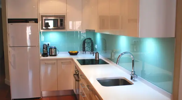 Modernos diseños de cocinas con encimeras blancas, electrodomésticos integrados y un salpicadero azul brillante que ilumina el espacio.