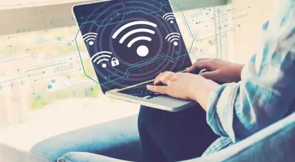Osoba pracuje na laptopie, na ekranie widoczne są ikony Wi-Fi i schematy. Dowiedz się, jak włączyć Wi-Fi w laptopie.