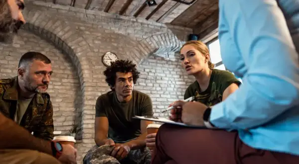 Grupa żołnierzy uczestniczy w sesji terapeutycznej, wspierając się nawzajem w procesie resocjalizacji.