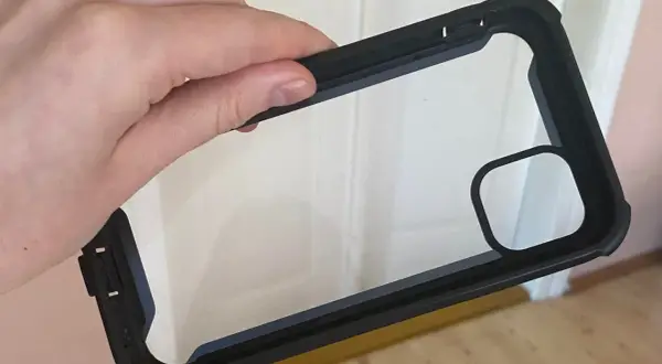 Dłoń trzyma czarne etui na telefon z przezroczystym tyłem. Dowiedz się, jak wyczyścić etui na telefon, aby wyglądało jak nowe.