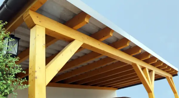 Holzkonstruktion eines Carports mit Trapezblechdach. Das Dach ist gut abgedichtet und schützt das darunter geparkte Auto.