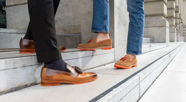Eleganckie mokasyny do jeansów, z pomarańczową podeszwą i frędzlami, idealne na spacer po mieście.