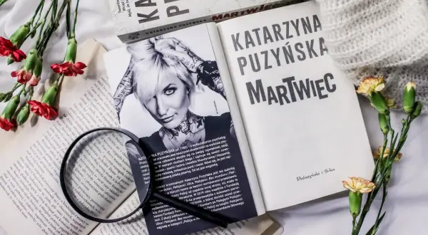 Książki Katarzyny Puzyńskiej, kwiaty i szkło powiększające na białym tle.