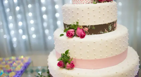 Elegancki tort weselny z różowymi różami i wstążkami. Idealny na uroczystość, jak piosenka do tortu weselnego.