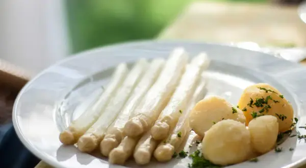 Ein Teller mit weißem Spargel und Salzkartoffeln, garniert mit Petersilie. Perfekt für einfache Spargel Rezepte.