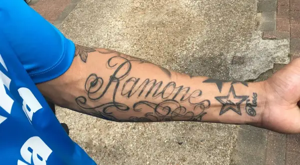 Damski tatuaż na przedramieniu z napisem "Ramone" i gwiazdką.