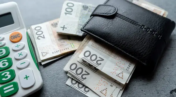 Kalkulator i portfel z polskimi banknotami 100 i 200 zł. Obliczenia wartości początkowej środka trwałego.