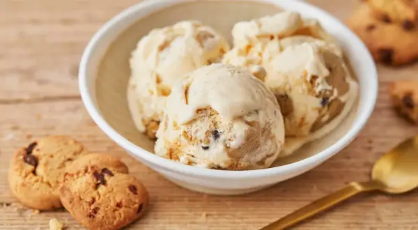 Schüssel mit cremigem Cookie Dough Eis, daneben Kekse und Löffel. Perfekt, um Cookie Dough Eis selber machen zu lernen.
