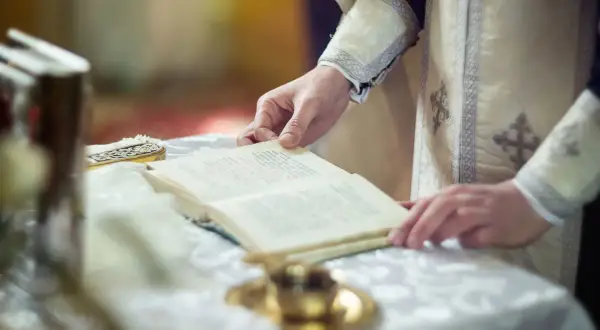 Dłoń duchownego trzyma księgę podczas nabożeństwa. Czas trwania rezurekcji jest nieznany, ale liturgia jest podniosła.