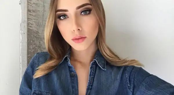 Młoda kobieta w dżinsowej koszuli, z makijażem i blond włosami, przypomina córkę Eminema.