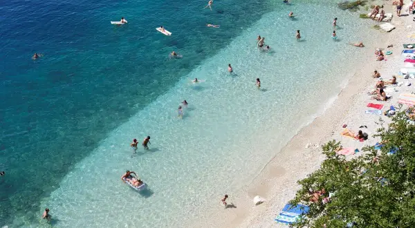 Słoneczne rijeka plaże z turkusową wodą. Ludzie pływają, opalają się i relaksują na kamienistym brzegu.