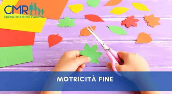 Mano di bambino che ritaglia forme di foglie colorate con forbici rosa, un'attività che stimola la motricità fine.