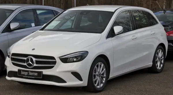 Biały mercedes hatchback z tabliczką "Junge Sterne" na grillu, gotowy do jazdy.
