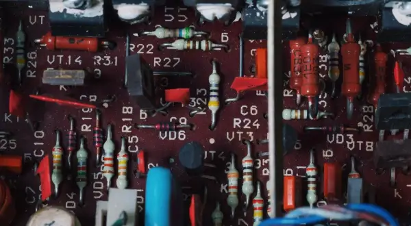 Wnętrze wzmacniacza samochodowego z widocznymi rezystorami, kondensatorami i innymi elementami elektronicznymi. To zdjęcie może pomóc zrozumieć, jak podłączyć wzmacniacz samochodowy.
