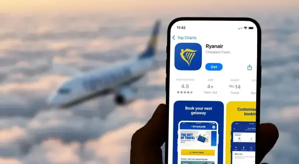 Telefon z aplikacją Ryanair, gotowy do odprawy online. W tle samolot lecący nad chmurami.