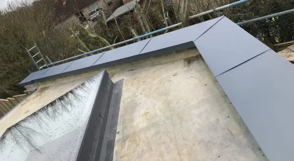 Nowa attyka z szarego metalu otacza dach z oknem dachowym.