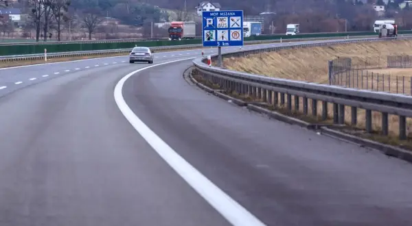 Autostrada z pasem awaryjnym. Znak informuje o MOP MSZANA, toalecie, busach i odległości 5 km.