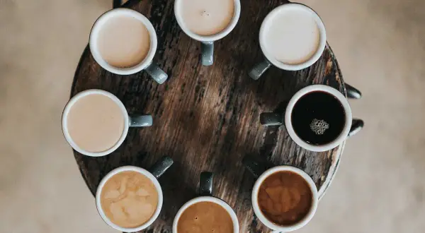 Åtta koppar kaffe i olika nyanser, från mörk espresso till ljus latte. En visuell guide till skillnad mellan latte och cappuccino.