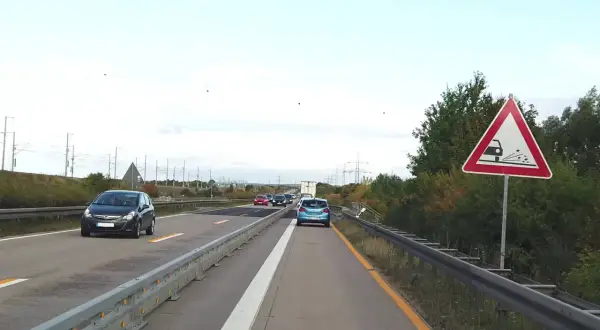 Achtung, stau schild warnt vor schleudernder Fahrbahn. Autos fahren auf der Autobahn.