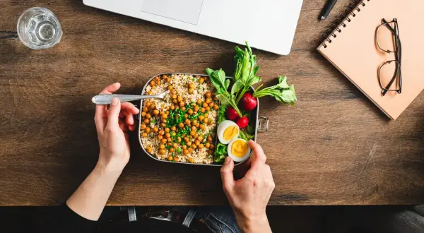 Pausa pranzo salutare con couscous, ceci, uova e verdure. La normativa sulla pausa pranzo incoraggia pasti equilibrati per il benessere lavorativo.