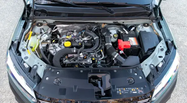 Vista del motor de un Dacia Sandero Stepway. Se aprecian componentes como la batería, el depósito de refrigerante y el sistema de admisión de aire.