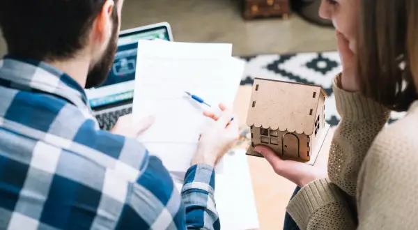 Pareja revisa documentos, planeando el futuro de su hogar, cuando un contrato de alquiler se convierte en indefinido.