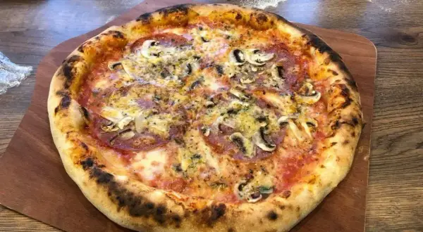 Pyszna pizza z pieczarkami i salami, idealnie wypieczona. Dowodzi, ile nagrzewa się kamień do pizzy, by uzyskać taki efekt.