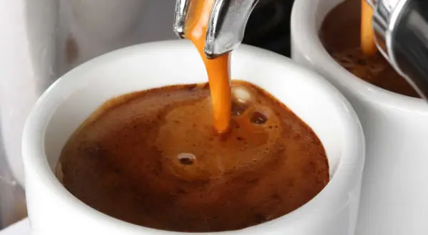 Caffè espresso che scende lentamente nella tazzina, creando una crema densa e invitante. Un piacere per gli occhi, se il caffè scende troppo piano, forse è ora di un caffè più forte.
