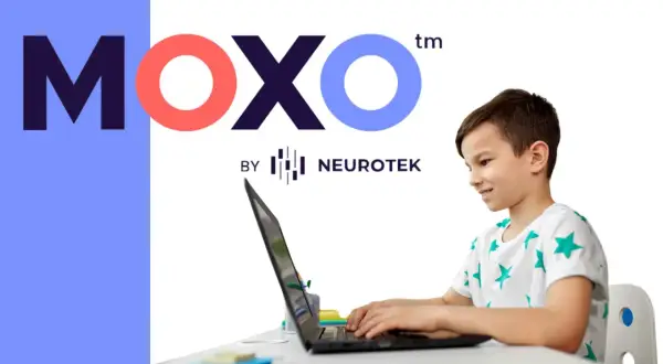 Chłopiec z uśmiechem pracuje przy laptopie, korzystając z platformy test moxo od Neurotek.