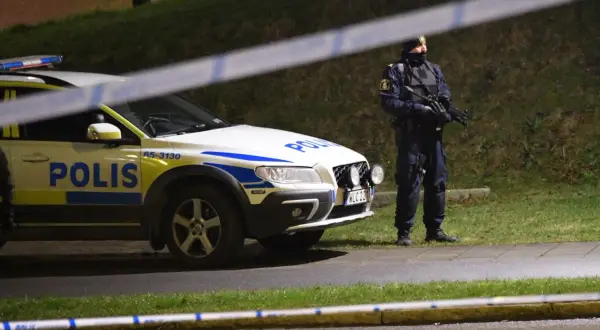 Polisbil och beväpnad polis, kanske Sandra Litzell, vid en avspärrning.