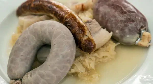 Eine bayerische Schlachtschüssel mit Blutwurst, Leberwurst und Bratwurst auf Sauerkraut.