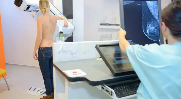 Frau wird mittels 3D Mammographie untersucht. Ärztin analysiert das Bild auf dem Monitor.