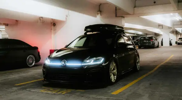 Svart VW Golf med takbox, redo för äventyr. Undrar hur mycket bensin en bil som denna drar?