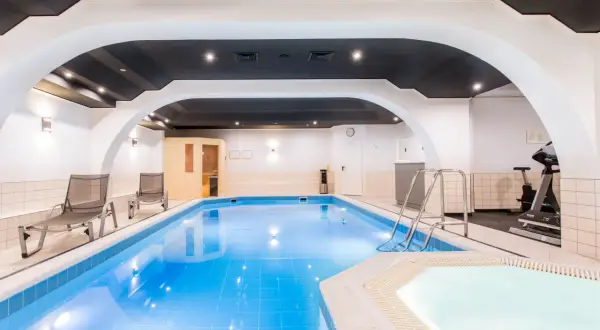 Basen i jacuzzi w hotelu Qubus Wrocław. Obok leżaki, sauna i sprzęt do ćwiczeń.