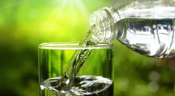 Verre rempli d'eau pure, versée d'une bouteille. L'eau du robinet, sans TDS, est rafraîchissante.