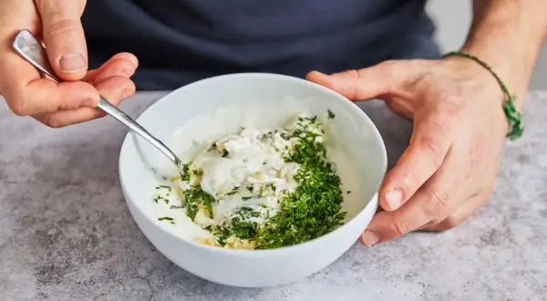 Ein cremiger Knoblauchdip mit frischer Petersilie wird zubereitet, perfekt als Beilage zu Flammlachs.