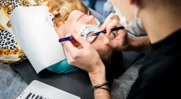 Profesjonalny kurs przedłużania rzęs, gdzie najlepiej? Stylistka precyzyjnie dokłada kępki.