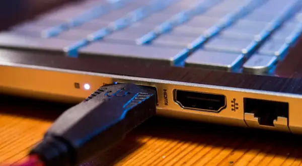 Podłączanie monitora do laptopa przez HDMI. Wtyczka kabla w porcie laptopa.