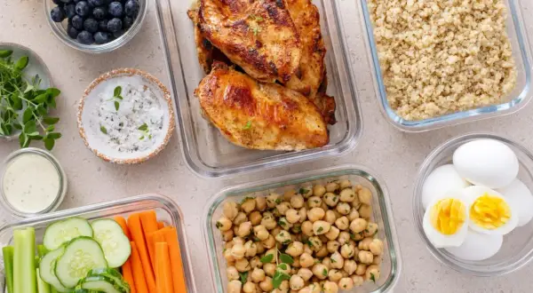 Vorbereitete Mahlzeiten für clean eating: Hähnchenbrust, Quinoa, Kichererbsen, Gemüse-Sticks, Blaubeeren und hartgekochte Eier.