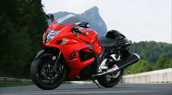 Czerwono-czarny motocykl Suzuki Hayabusa 1300 na drodze, z górami w tle.