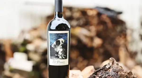 En flaska "The Prisoner" Cabernet Sauvignon står på en träbit. Etiketten visar en hund i kedjor, vilket ger en hint om hur detta vin kan kallas.