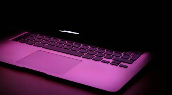 Klawiatura MacBooka w różowym świetle. Chcesz wiedzieć, jak zrobic @ na macbook? To proste: Option + 2.