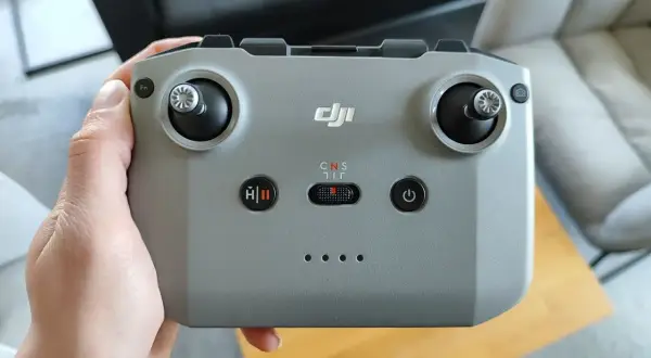 Dłoń trzyma szary kontroler DJI, gotowy do sterowania dronem.