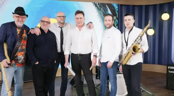 Zespół Mr. Zoob gotowy do występu. Muzycy w białych koszulach i jeansach, jeden z gitarą, drugi z saksofonem. "Mój jest ten kawałek podłogi" - tekst piosenki.
