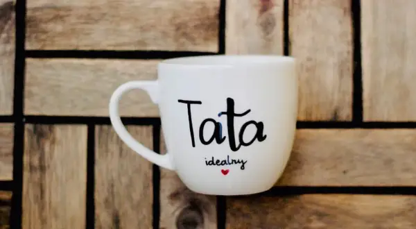 Biały kubek z napisem "Tata idealny" i serduszkiem. Świetny pomysł, jak zrobić prezent dla taty.
