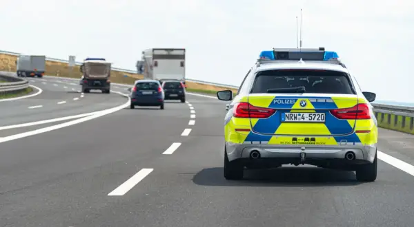 Niemieckie autostrady: radiowóz policyjny z włączonymi sygnałami świetlnymi jedzie za innymi pojazdami.