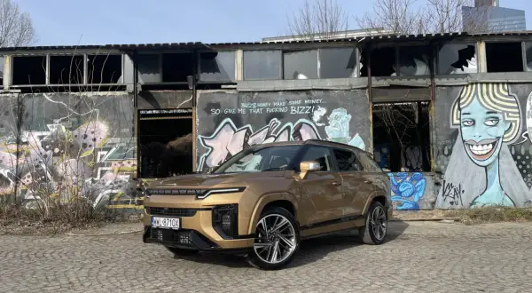 Złoty SsangYong Actyon na tle zniszczonego budynku z graffiti.