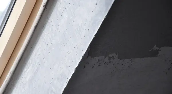 Fragment ściany z betonem architektonicznym i drewnianą ramą okienną. Zastanawiasz się, jak usunąć beton architektoniczny ze ściany?