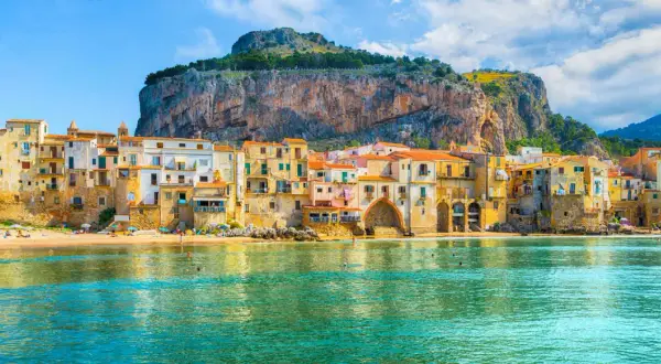 Case colorate affacciate sul mare di Cefalù, con la Rocca a dominare lo sfondo.