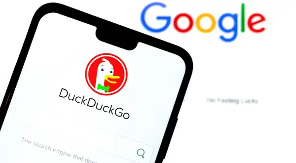 Telefon z DuckDuckGo, jedną z wyszukiwarek internetowych, obok rozmazanego logo Google.
